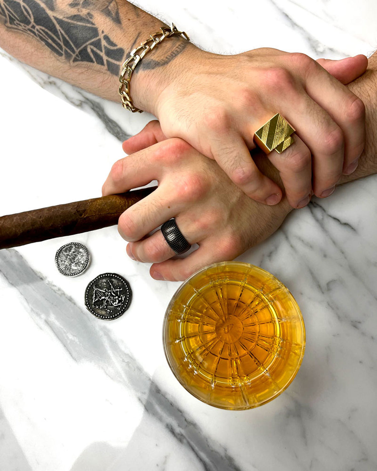 male hands wearing rings, marble, whiskey, cigar, ancient coins, gold, rhodium, luxury